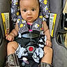 attention, baby, car_interior, car_seat, child, cowboy_boots, cute, dress, expression, floral_pattern, indoors, infant, portrait, safety_harness, seat_padding, seatbelt, small_hands, strapped_in, wide_eyes, young_child