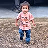 child, toddler, walking, standing, pink_shirt, blue_jeans, curly_hair, portrait, outdoor, street, pavement, asphalt, vehicle, adult, legs, face, young_child, casual_clothing, front_view, daylight