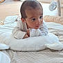 baby, infant, play_mat, pillow, white_clothing, indoor, floor, toy, rocking_chair, window, curious, child, soft_toys, nursery, wooden_floor, striped_pattern, cushion, face, person, early_morning_light