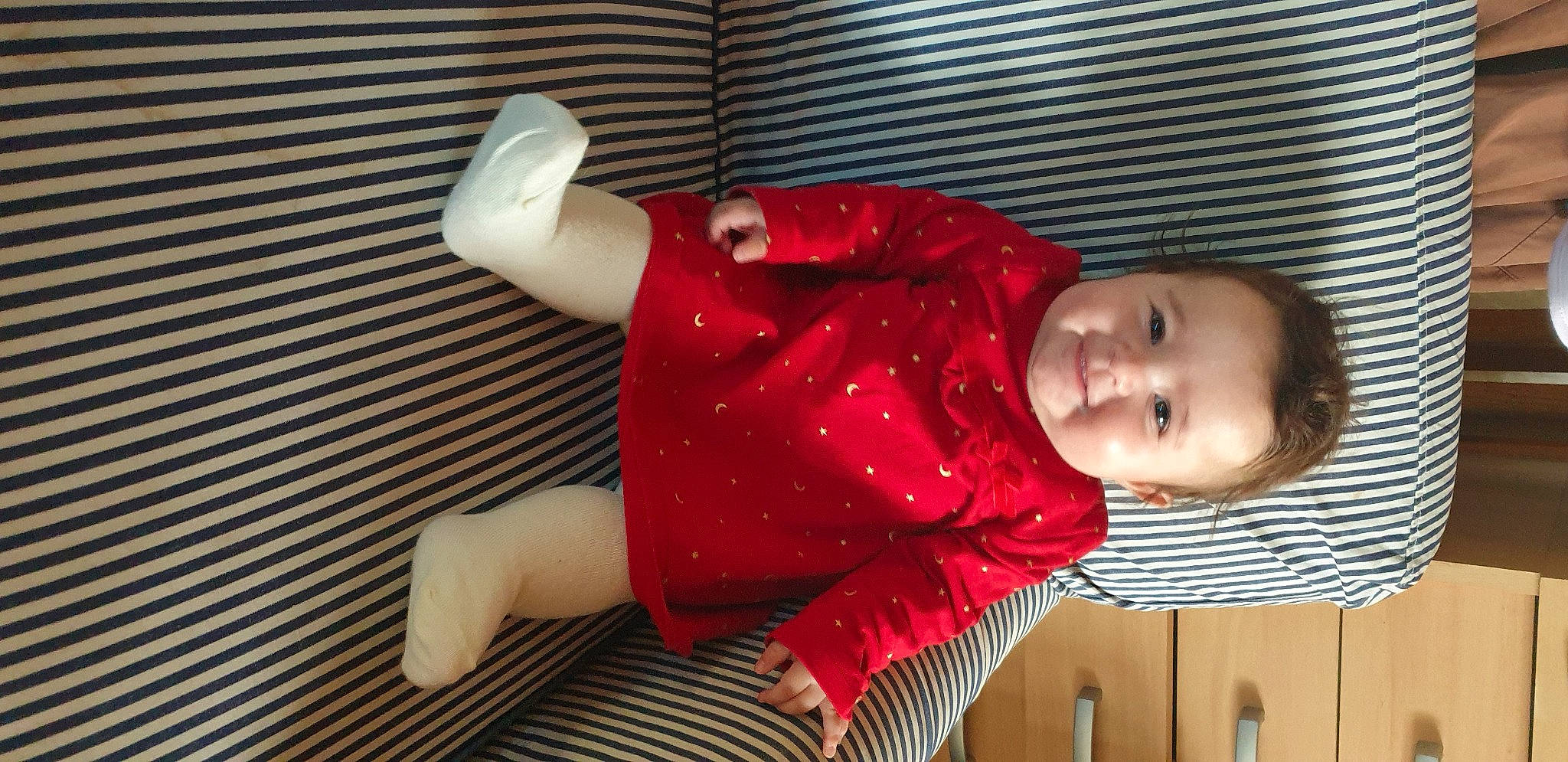 Myla participe au concours pour gagner de l'argent avec cette photo : arm, baby, baby_products, baby_toddler_clothing, carmine, comfort, elbow, flooring, fun, hand, happy, human_leg, joy, knee, pattern, person, red, sitting, sleeve, smile