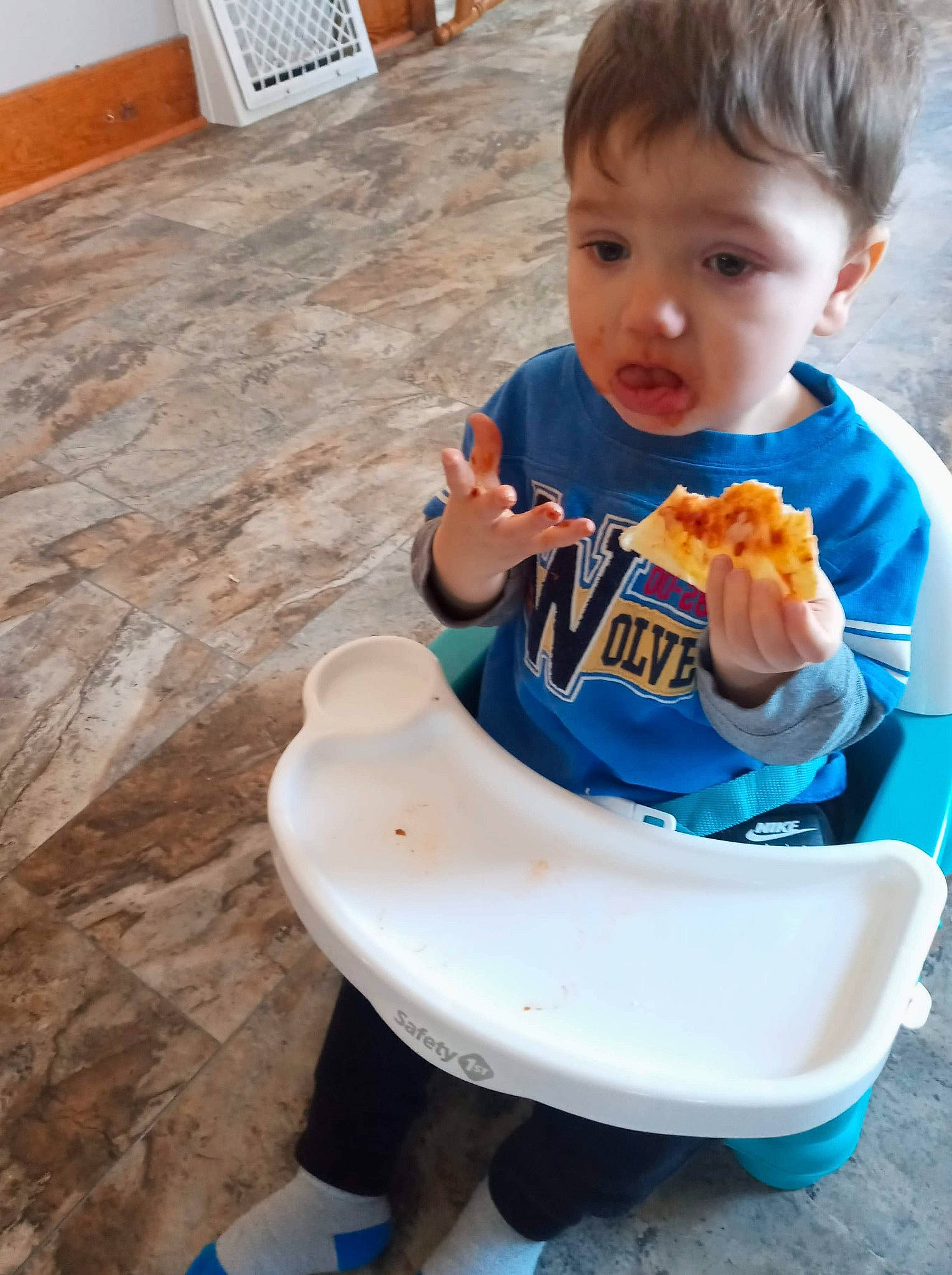 Liam is registered to the contest to win money with this photo: baby, baby_food, chair, child, comfort_food, cuisine, dish, eating, flooring, food, food_craving, hardwood, junk_food, person, plate, sitting, t_shirt, tableware, toddler, wood