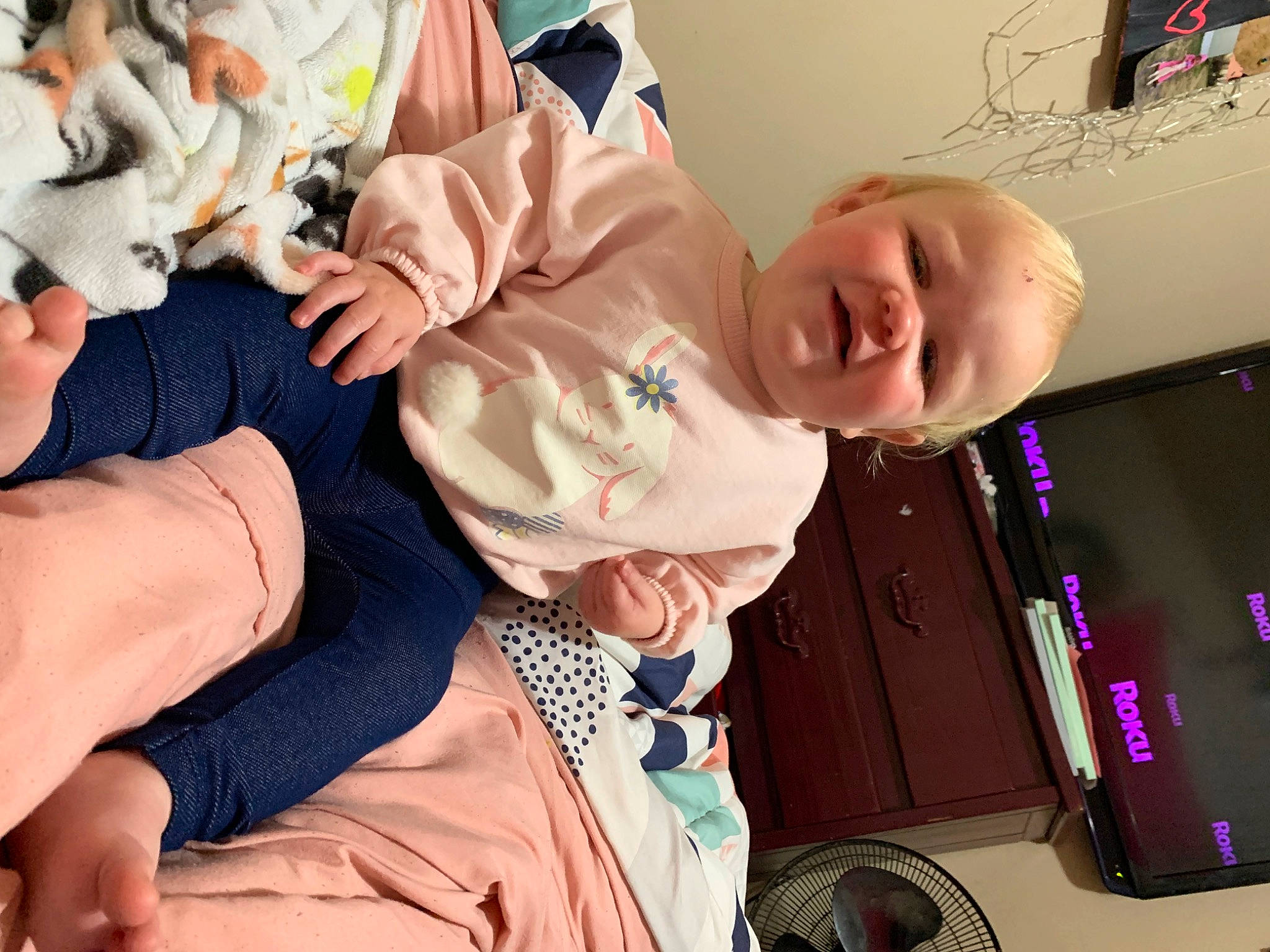 Oaklee is registered to the contest to win money with this photo: baby, baby_products, baby_toddler_clothing, child, comfort, event, finger, fun, gesture, happy, lap, person, pink, portable_communications_device, room, sitting, smile, toddler