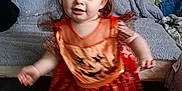 Harper joined the competition — help win amazing prizes! toddler, child, orange_dress, pumpkin_face, headband, barefoot, carpet, couch, blanket, indoor, motion_blur, smiling, cute, baby, person, home, wall_photos, furniture, fabric, playful