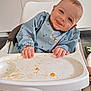 baby, high_chair, food, messy, smiling, bib, clothing, face, hand, foot, indoor, kitchen, child, cute, expression, sitting, table, feeding, infant, happy