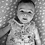 baby, infant, face, eyes, clothing, pattern, blanket, lying_down, cute, portrait, sleeveless_shirt, palm_tree_pattern, buttoned_shirt, indoors, young_child, skin, expression, head, person, monochrome