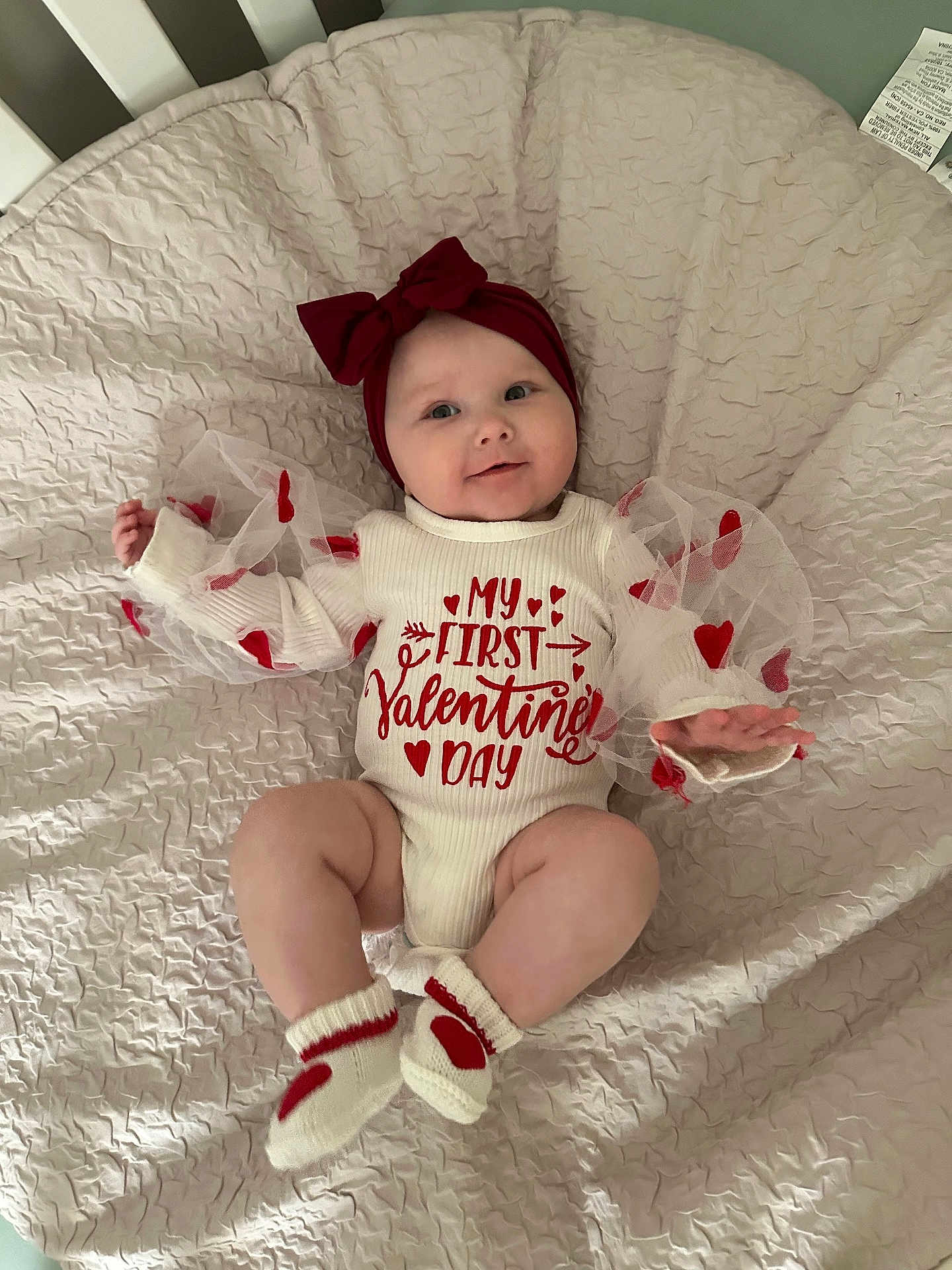 Kamrynn is registered to the contest to win money with this photo: baby, infant, valentines_day, headband, bow, socks, heart_pattern, cushion, blanket, soft_texture, smiling, cute, holiday_outfit, toddler, lying_down, indoors, celebration, child, portrait, clothing