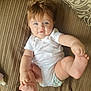 Bonnie is registered to the contest to win money with this photo: baby, infant, blue_eyes, playing, couch, diaper, white_onesie, curly_hair, happy, cute, indoor, soft_light, toddler, child, smiling, person, furniture, texture, relaxed, bottle