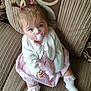 baby, blue_eyes, child, comfortable, couch, cute, girl, hair_ties, indoors, infant, looking_up, pacifier, pigtails, pink_dress, plush, portrait, seated, socks, soft_lighting, white_cardigan