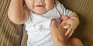Bonnie joined the competition — help win amazing prizes! baby, infant, blue_eyes, smile, hand, couch, white_onesie, playful, happy, skin, person, child, indoor, cute, face, young, human, fingers, holding, seated