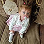 adorable, baby, blue_eyes, child, couch, cute, fabric, hair_ties, home, indoor, infant, looking_up, pacifier, pink_dress, portrait, seated, socks, soft_lighting, white_cardigan, young_child