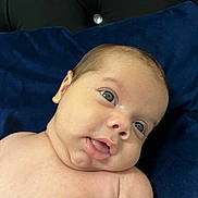 Izac a rejoint le concours — aidez-le/la à gagner de superbes lots ! baby, infant, face, skin, eyes, mouth, cheeks, shoulder, blue_cushion, black_background, portrait, closeup, newborn, expression, curious, lying_down, indoors, soft_light, child, human