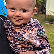 Barrett joined the competition — help win amazing prizes! baby, child, smiling, outdoor, camouflage_clothing, person, face, tongue, hand, grass, garden, portrait, cute, holding, young_child, nature, expression, happy, head, skin