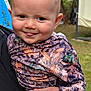 baby, child, smiling, outdoor, camouflage_clothing, person, face, tongue, hand, grass, garden, portrait, cute, holding, young_child, nature, expression, happy, head, skin