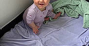 Embyr is registered to the contest to win money with this photo: baby, blanket, bright_eyes, child, cozy, cute, fabric, face, happy, indoor, infant, light, person, playpen, purple_clothing, sitting, smiling, soft_texture, towel, young_child