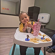 Katalina joined the competition — help win amazing prizes! toddler, child, high_chair, food, fries, chicken_nuggets, sippy_cup, pink_cup, yellow_shirt, smiling, indoor, flooring, window, reflection, furniture, person, happy, snack, cute, baby