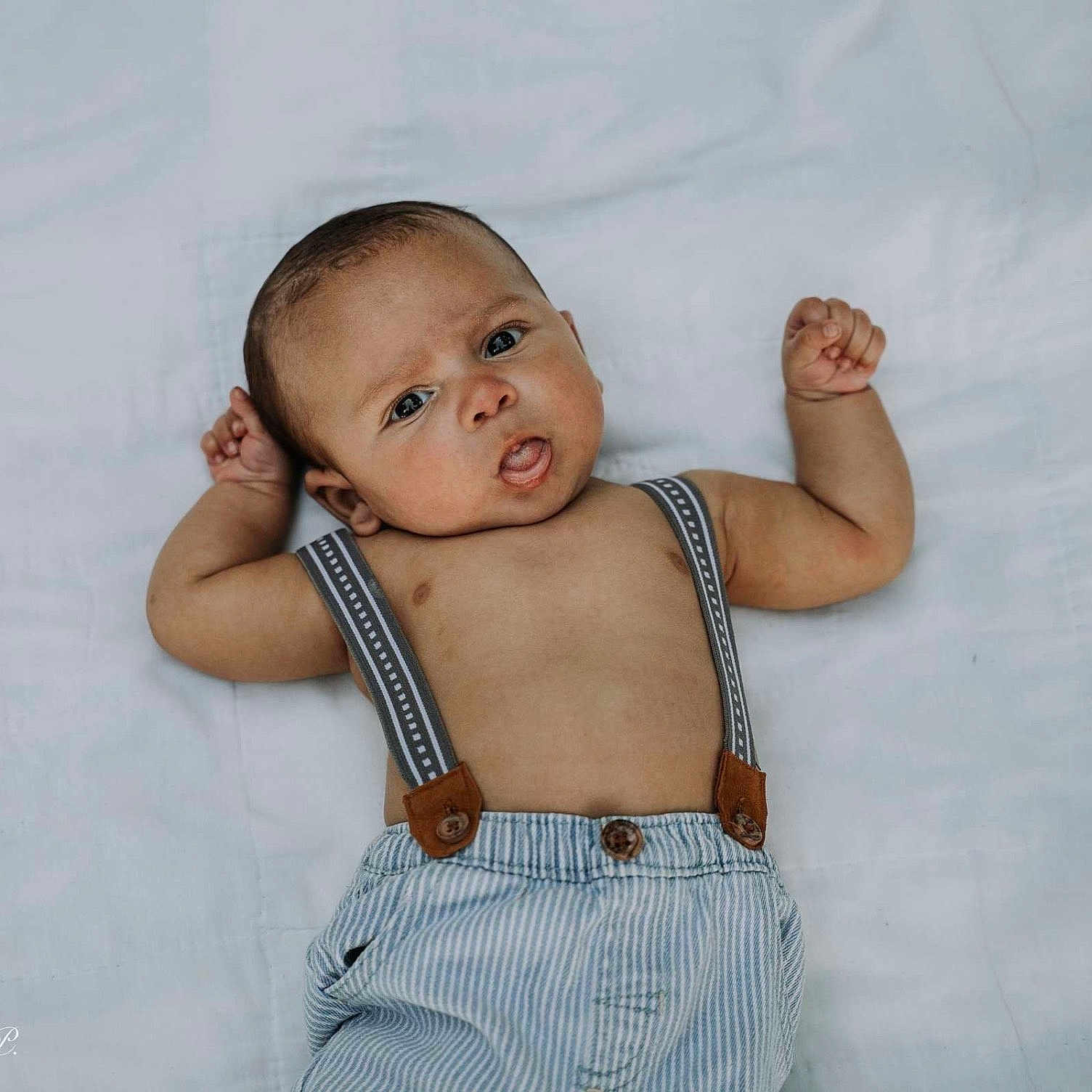 Jaleel is registered to the contest to win money with this photo: adorable, arms_up, baby, baby_face, casual_clothing, child, curious, cute, expression, indoors, infant, lying_down, one_person, portrait, skin, small_hands, striped_pants, suspenders, white_background, young