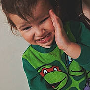 Greyson joined the competition — help win amazing prizes! toddler, child, person, face, smile, hand, clothing, sweater, cartoon_characters, teenage_mutant_ninja_turtles, hair, indoor, wall, expression, playful, closeup, adult, partial_face, skin, portrait