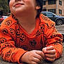 toddler, child, sweater, pumpkin_pattern, black_beanie, outdoor, concrete, car, building, trees, autumn, fall, cute, portrait, person, clothing, casual, daytime, smile, young