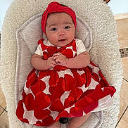 Keïssy a rejoint le concours — aidez-le/la à gagner de superbes lots ! baby, infant, red_dress, headband, baby_seat, cozy, hands, feet, indoor, floor_tiles, patterned_clothing, cute, portrait, child, smiling, baby_accessory, soft_texture, person, sitting, comfortable