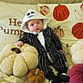 Milo is registered to the contest to win money with this photo: baby, child, costume, halloween, pumpkin, plush, pillow, couch, face, hood, black_and_white, striped, cute, autumn, decor, soft, indoor, footwear, sitting, cozy