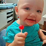 Oaklynn is registered to the contest to win money with this photo: bald_head, blue_shirt, candy, casual, child, closeup, comfort, cute, face, hand, happy, indoor, lollipop, messy_mouth, person, sitting, smiling, toddler, toy, young_child