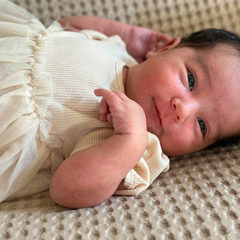 Hinatea participe au concours pour gagner de l'argent avec cette photo : baby, blanket, child, closeup, clothing, cute, dress, face, hand, indoors, infant, lying, natural_light, newborn, person, portrait, skin, soft, texture, young