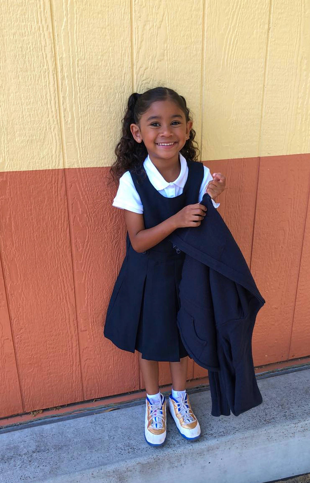 Aniyah is registered to the contest to win money with this photo: child, electric_blue, event, formal_wear, fun, happy, human_leg, jewellery, joy, knee, person, room, school_uniform, shoe, sitting, sleeve, smile, sock, t_shirt, thigh