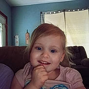 Mackenzie joined the competition — help win amazing prizes! child, girl, toddler, portrait, smiling, happy, indoors, couch, home, window, curtains, blue_wall, pink_shirt, blonde_hair, face, eyes, hand, sitting, family_room, daylight