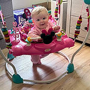 Maci joined the competition — help win amazing prizes! baby, child, pink_clothing, jumper, toy, minnie_mouse, playroom, floor, window, sunlight, face, smile, playful, indoor, furniture, colorful, baby_toys, happy, infant, seat