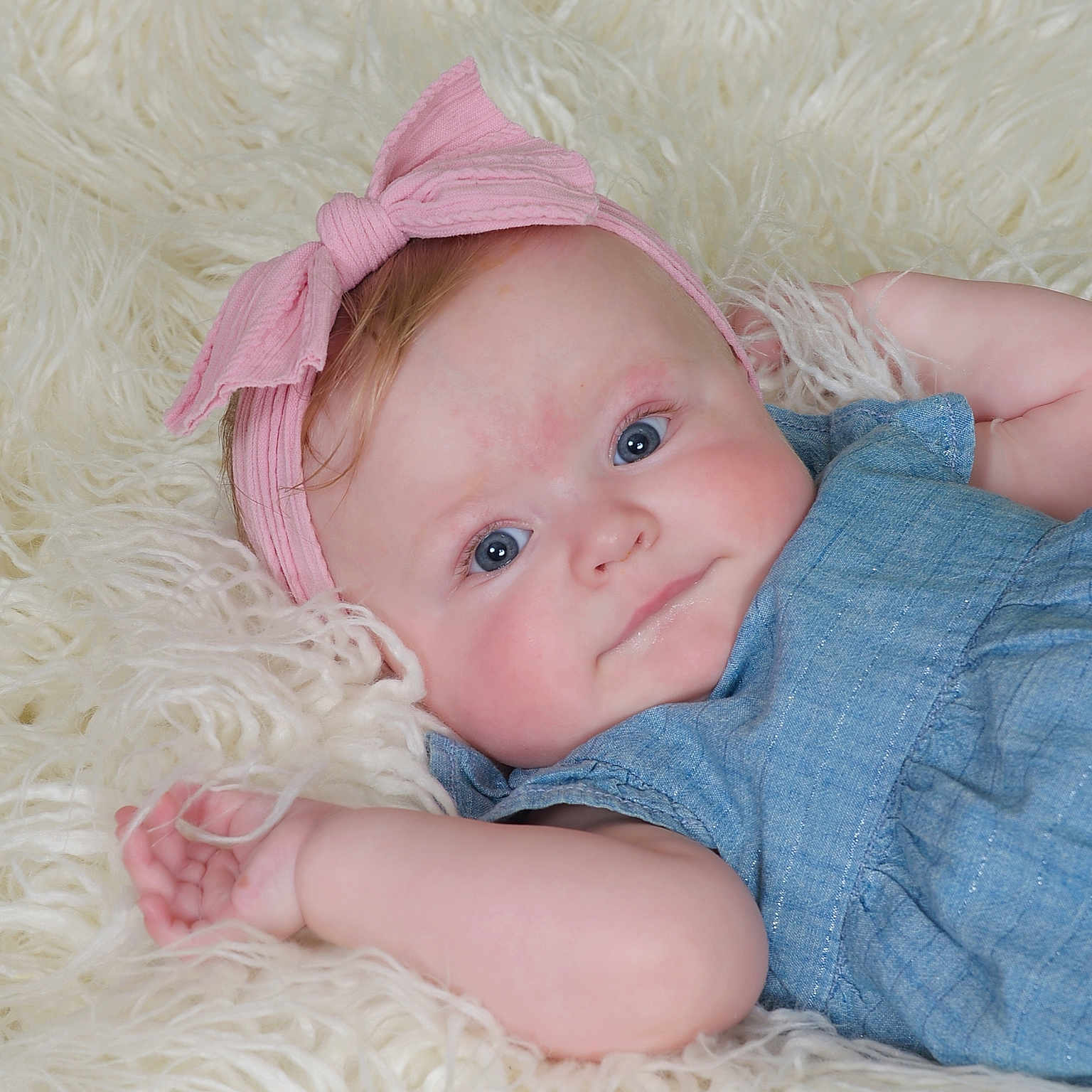 Maci is registered to the contest to win money with this photo: adorable, baby, blue_dress, blue_eyes, child, closeup, cozy, cute, face, fluffy_rug, hand, headband, indoor, infant, laying_down, portrait, skin, smile, soft_texture, young