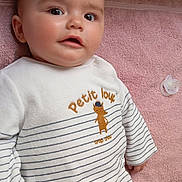 Kenny a rejoint le concours — aidez-le/la à gagner de superbes lots ! baby, child, infant, face, eyes, clothing, striped_outfit, pacifier, pink_towel, lying_down, cute, soft_texture, skin, hand, portrait, closeup, indoors, expression, looking, small