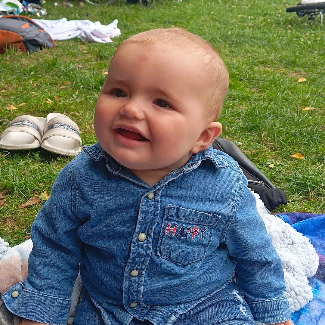 Kenny a rejoint le concours — aidez-le/la à gagner de superbes lots ! adult, baby, blanket, casual_clothing, child, daylight, denim_clothing, family, footwear, grass, greenery, happy, nature, outdoor, park, person, relaxation, sitting, smile, wheelchair