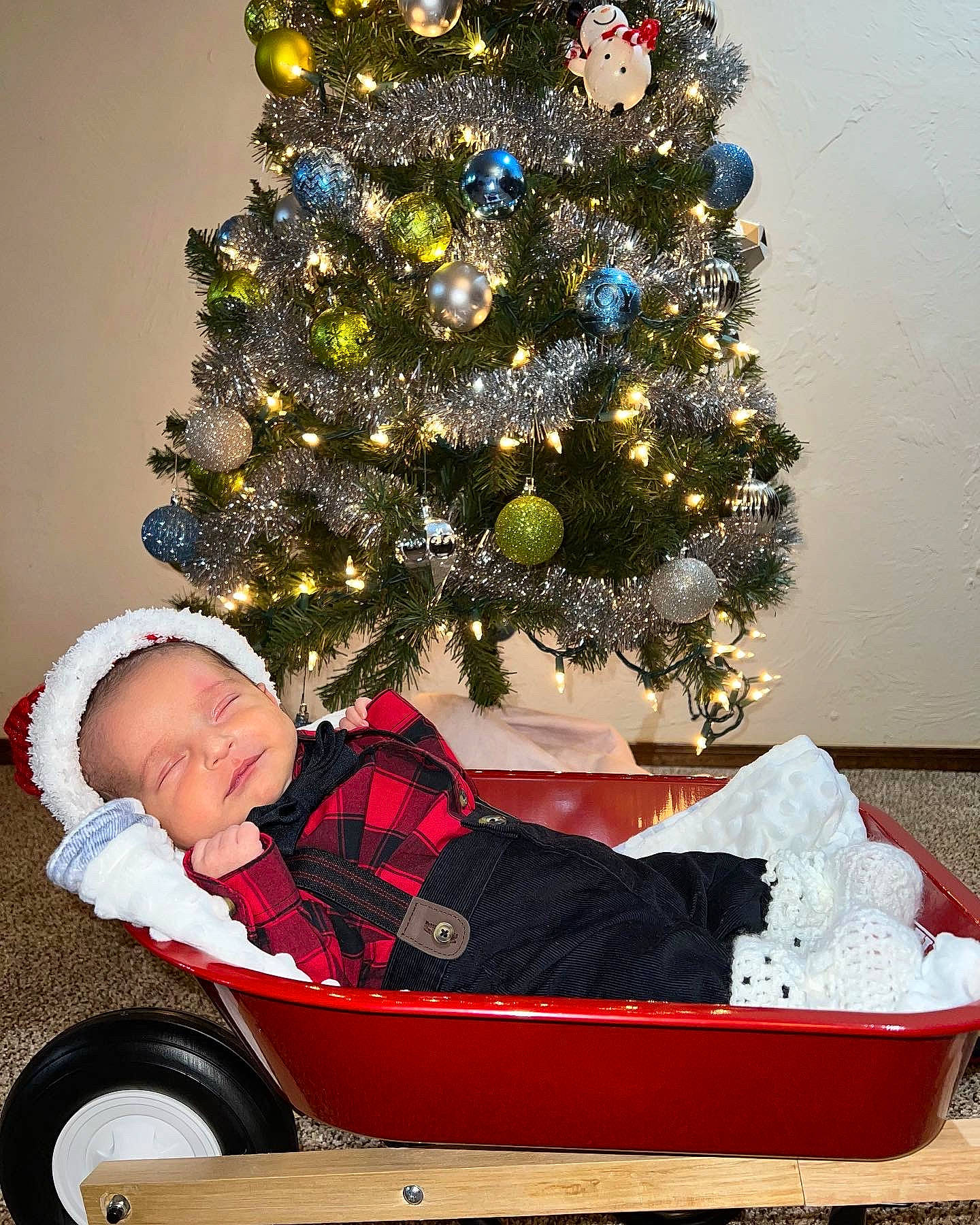 Noah joined the competition — help win amazing prizes! cart, christmas_decoration, christmas_ornament, christmas_tree, conifer, event, evergreen, holiday, holiday_ornament, ornament, person, plant, sitting, sled, tire, toddler, tree, vehicle, wheel, white