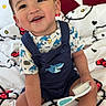 toddler, child, smiling, sitting, bed, hello_kitty, bedding, brush, clothing, shark, footwear, sneakers, indoor, cute, happy, person, face, toy, furniture, playful
