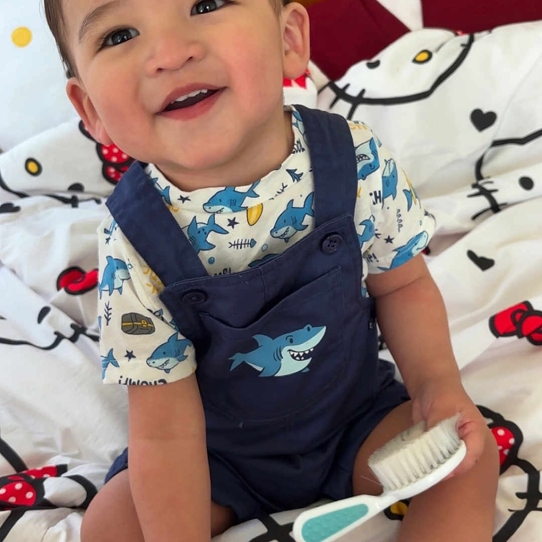 Daniel joined the competition — help win amazing prizes! toddler, child, smiling, sitting, bed, hello_kitty, bedding, brush, clothing, shark, footwear, sneakers, indoor, cute, happy, person, face, toy, furniture, playful