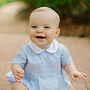Liam is registered to the contest to win money with this photo: baby, child, smiling, sitting, blue_dress, white_collar, outdoor, nature, happy, face, skin, hands, legs, pavement, background_blur, cute, young, portrait, infant, bright