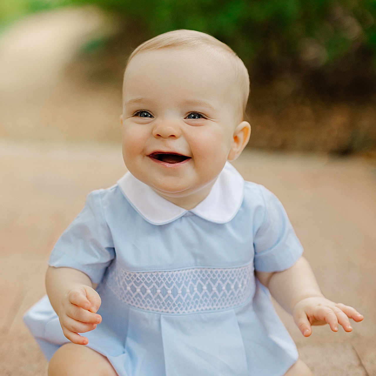 Liam is registered to the contest to win money with this photo: baby, background_blur, blue_dress, bright, child, cute, face, hands, happy, infant, legs, nature, outdoor, pavement, portrait, sitting, skin, smiling, white_collar, young