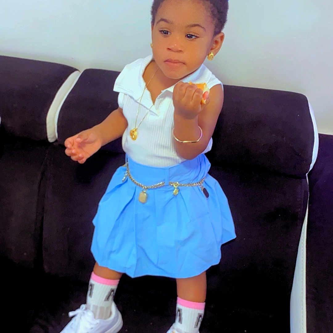 Dorianna Kapita participe au concours pour gagner de l'argent avec cette photo : accessories, bodypart, child, clothing, couch, face, female, finger, footwear, furniture, girl, hand, head, person, photography, portrait, shoe, shorts, skirt, sunglasses