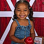 child, toddler, smiling, denim_dress, pigtails, apple, red_apple, holding, portrait, studio, barn_backdrop, rustic, happy, cute, face, person, young_child, seated, indoor, photography