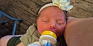 Myralyn is registered to the contest to win money with this photo: arm, baby, bottle_feeding, closeup, clothing, comfort, cute, feeding, flower, hand, headband, indoor, infant, newborn, person, resting, skin, sleeping, toddler, wooden_floor