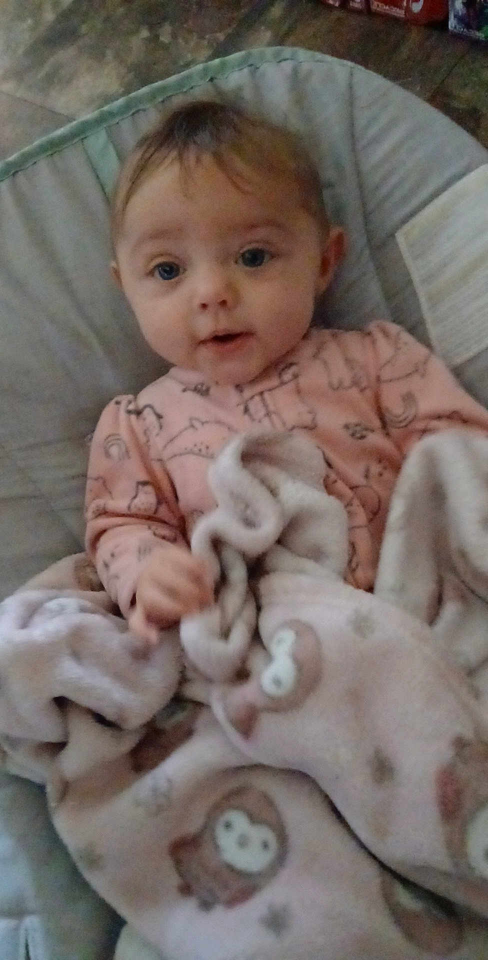 Myralyn is registered to the contest to win money with this photo: baby, child, blanket, pink_clothing, owl_pattern, onesie, infant, face, cushion, indoor, floor, tiled_floor, cute, young_child, portrait, cozy, soft_texture, seated, curious, hand