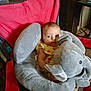 baby, baby_seat, blue_eyes, child, comfort, cushion, cute, elephant, expression, face, furniture, indoors, infant, person, plush_toy, red_chair, seated, soft_toy, strawberry_print, yellow_clothing