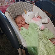 Myralyn is registered to the contest to win money with this photo: baby, sleeping, unicorn, plush_toy, blanket, baby_rocker, infant, cozy, soft, peaceful, child, indoors, resting, cute, toy, carpet, bottle, box, furniture, nap