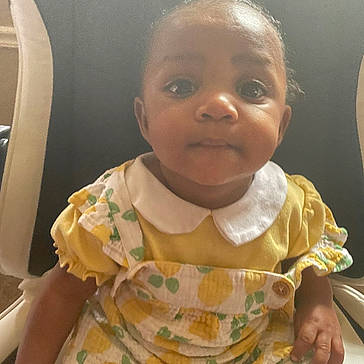 Josiah joined the competition — help win amazing prizes! baby, chair, child, collar, curious, cute, eyes, face, hair, hands, indoor, infant, patterned_clothing, person, portrait, short_sleeves, sitting, skin, yellow_dress, young_child
