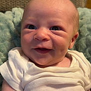 Colton is registered to the contest to win money with this photo: baby, infant, smile, white_onesie, soft_blanket, cushion, face, skin, person, cute, newborn, happy, indoors, child, head, eyes, mouth, arm, expression, portrait