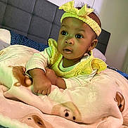 Avalynn is registered to the contest to win money with this photo: baby, child, blanket, headband, yellow_clothing, bed, pillow, face, infant, curious, indoors, soft_texture, animal_print, cute, portrait, resting, young_child, cozy, sleep_area, warm