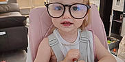 Agathe a rejoint le concours — aidez-le/la à gagner de superbes lots ! toddler, child, glasses, high_chair, indoor, living_room, table, curious, smile, blond_hair, baby, person, furniture, window, curtains, television, cabinet, toy, clothing, face
