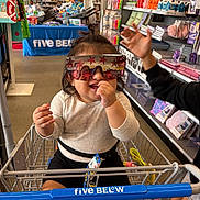 Kiara joined the competition — help win amazing prizes! aisle, baby, casual, child, clothing, colorful, fun, hand, happy, indoor, person, playful, retail, shelf, shopping_cart, smiling, store, sunglasses, toddler, toys