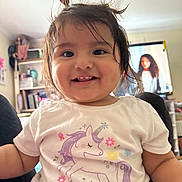Kiara joined the competition — help win amazing prizes! toddler, child, smiling, unicorn, shirt, hair, pigtails, indoors, home, bookshelf, furniture, person, cute, happy, portrait, baby, face, clothing, young_child, living_room