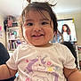 toddler, child, smiling, unicorn, shirt, hair, pigtails, indoors, home, bookshelf, furniture, person, cute, happy, portrait, baby, face, clothing, young_child, living_room
